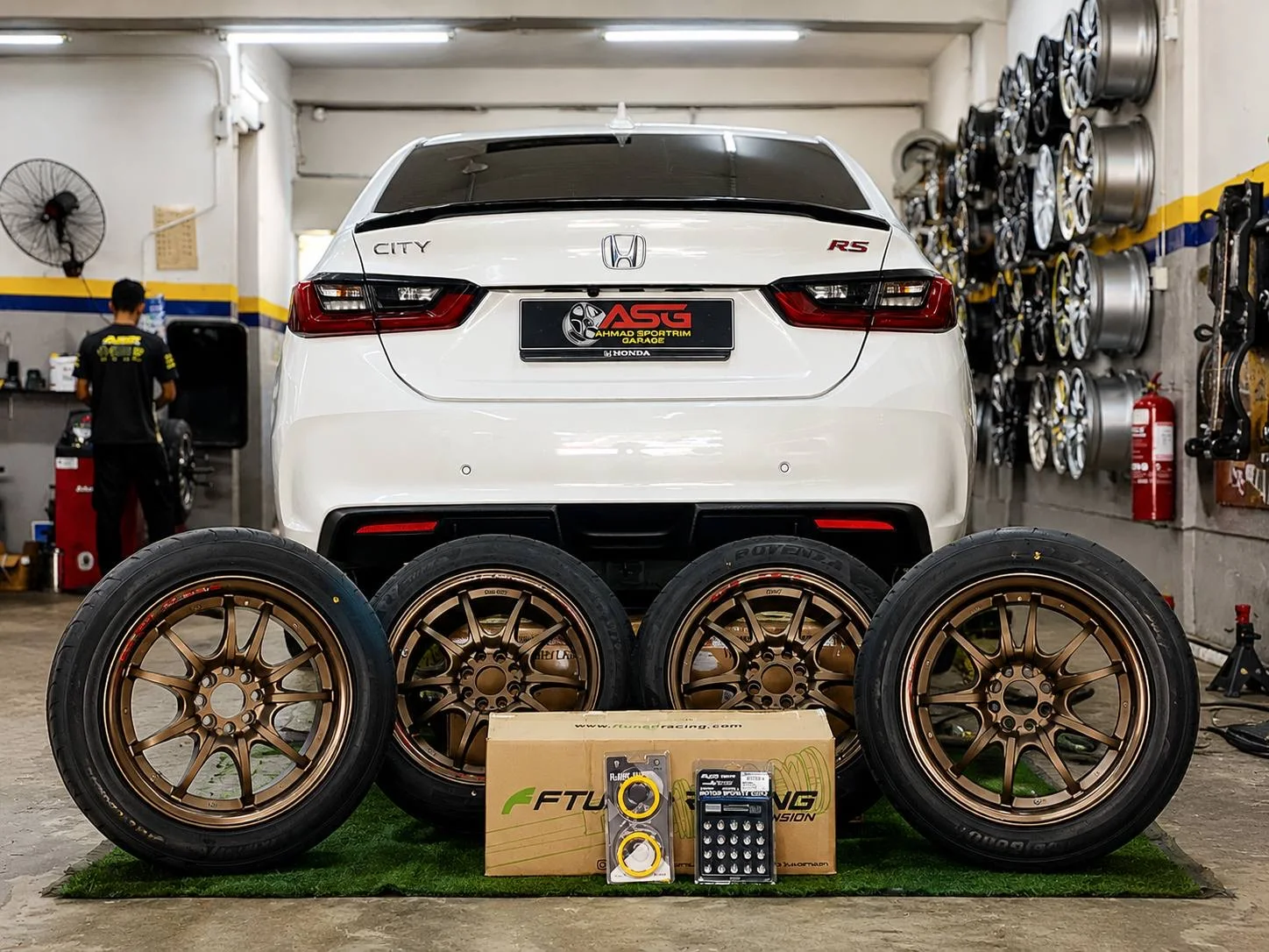 White Honda City with four bronze wheels displayed at the ASG workshop