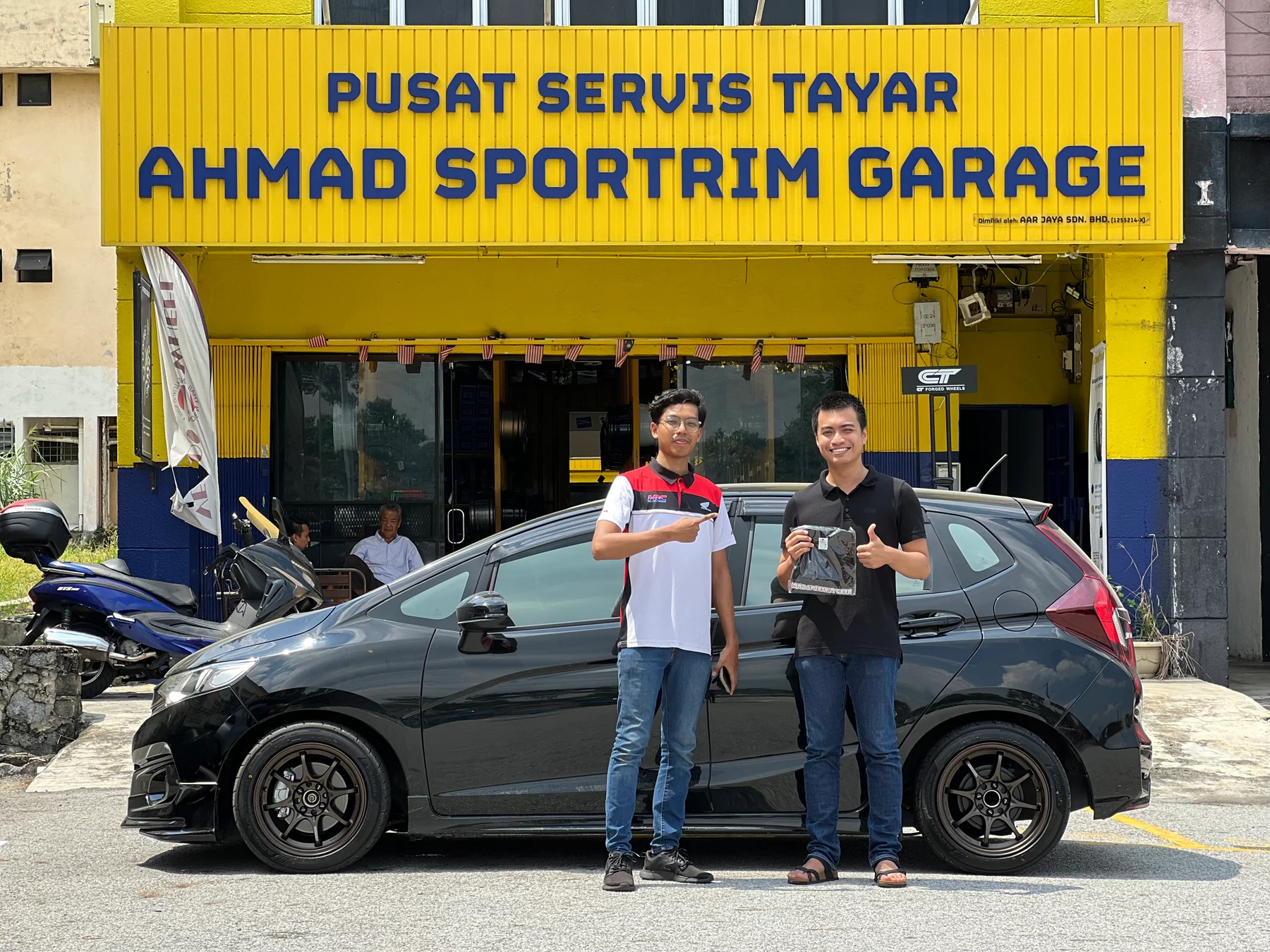 ASG team member and customer with a black car outside Ahmad Sportrim Garage