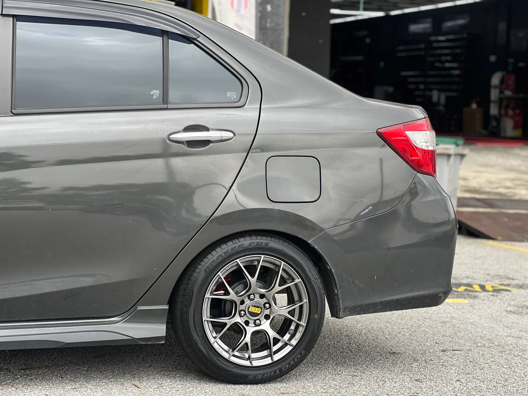 Grey Perodua Bezza rear side view with a multi-spoke sport wheel