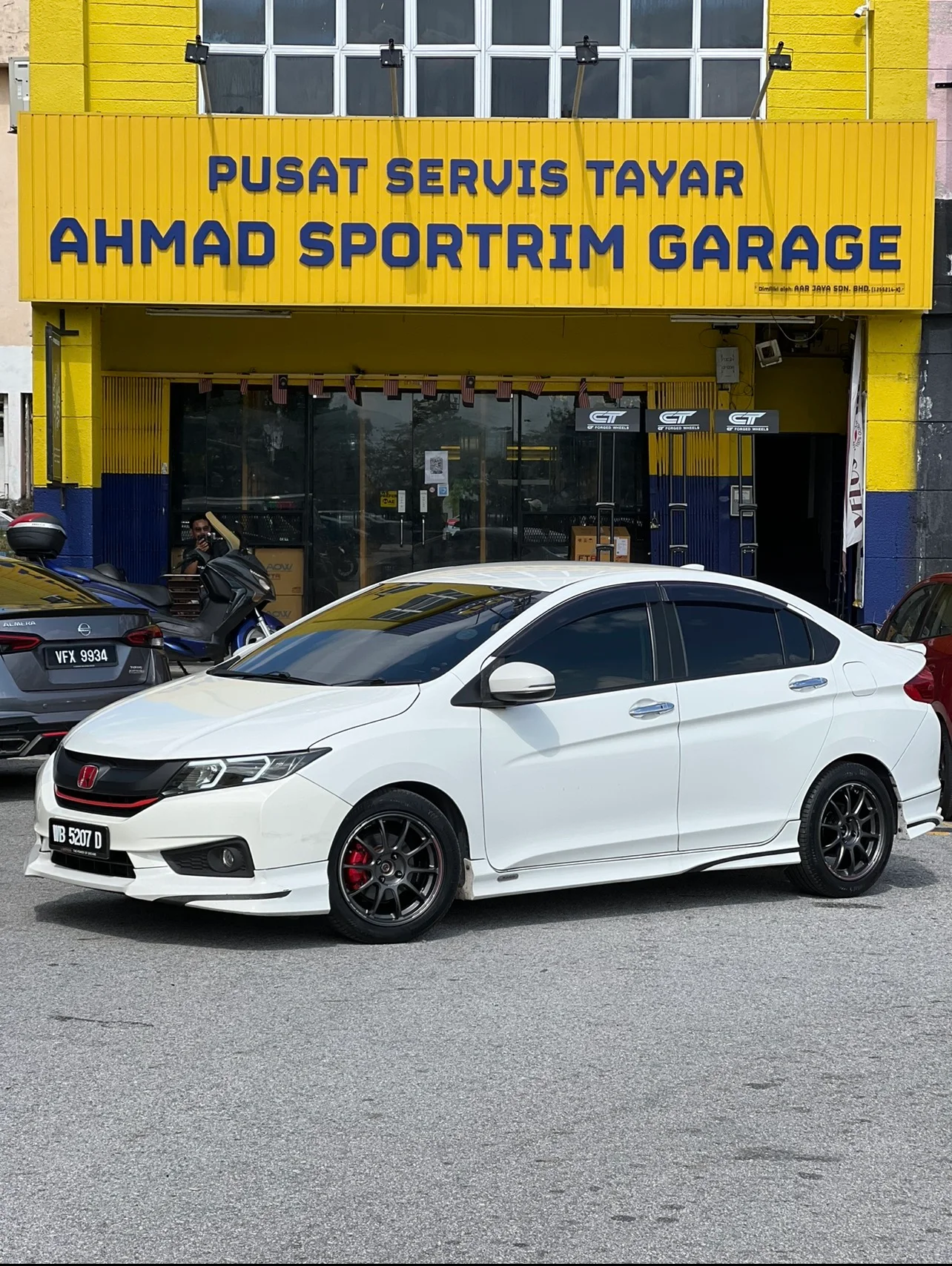 White Honda City with dark multi-spoke performance wheels outside ASG