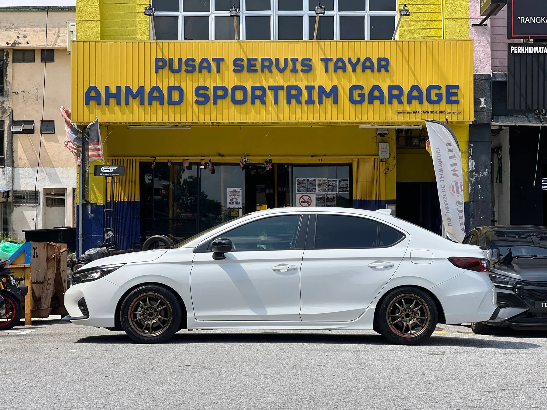 White Honda City side profile with bronze multi-spoke wheels outside ASG