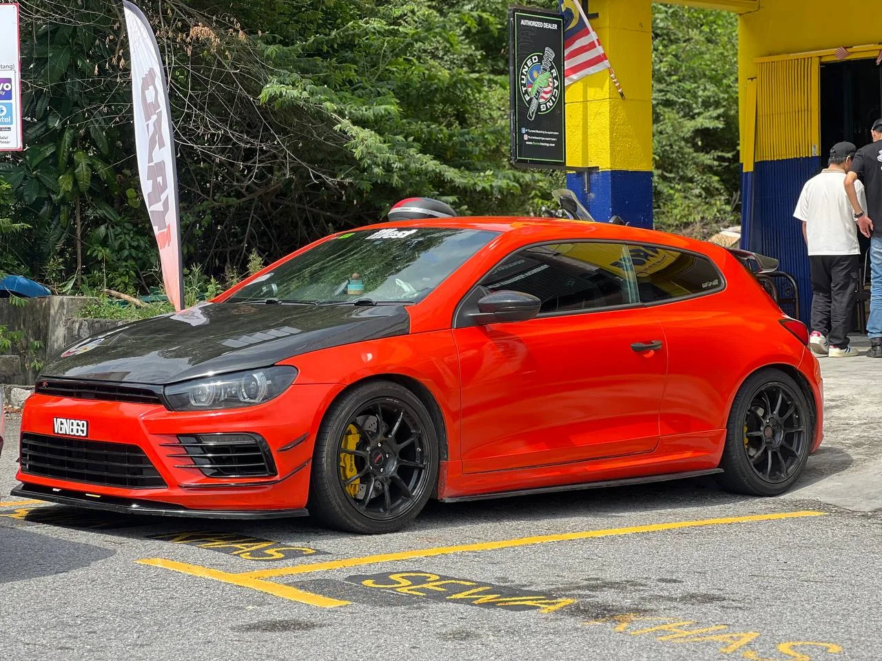 Red Volkswagen hatchback with dark performance wheels