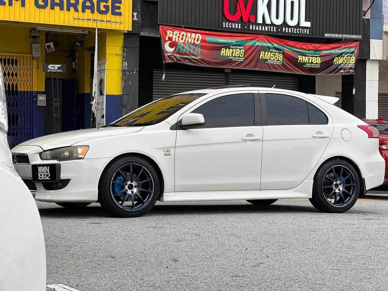 White Mitsubishi Lancer sedan with dark multi-spoke wheels outside ASG