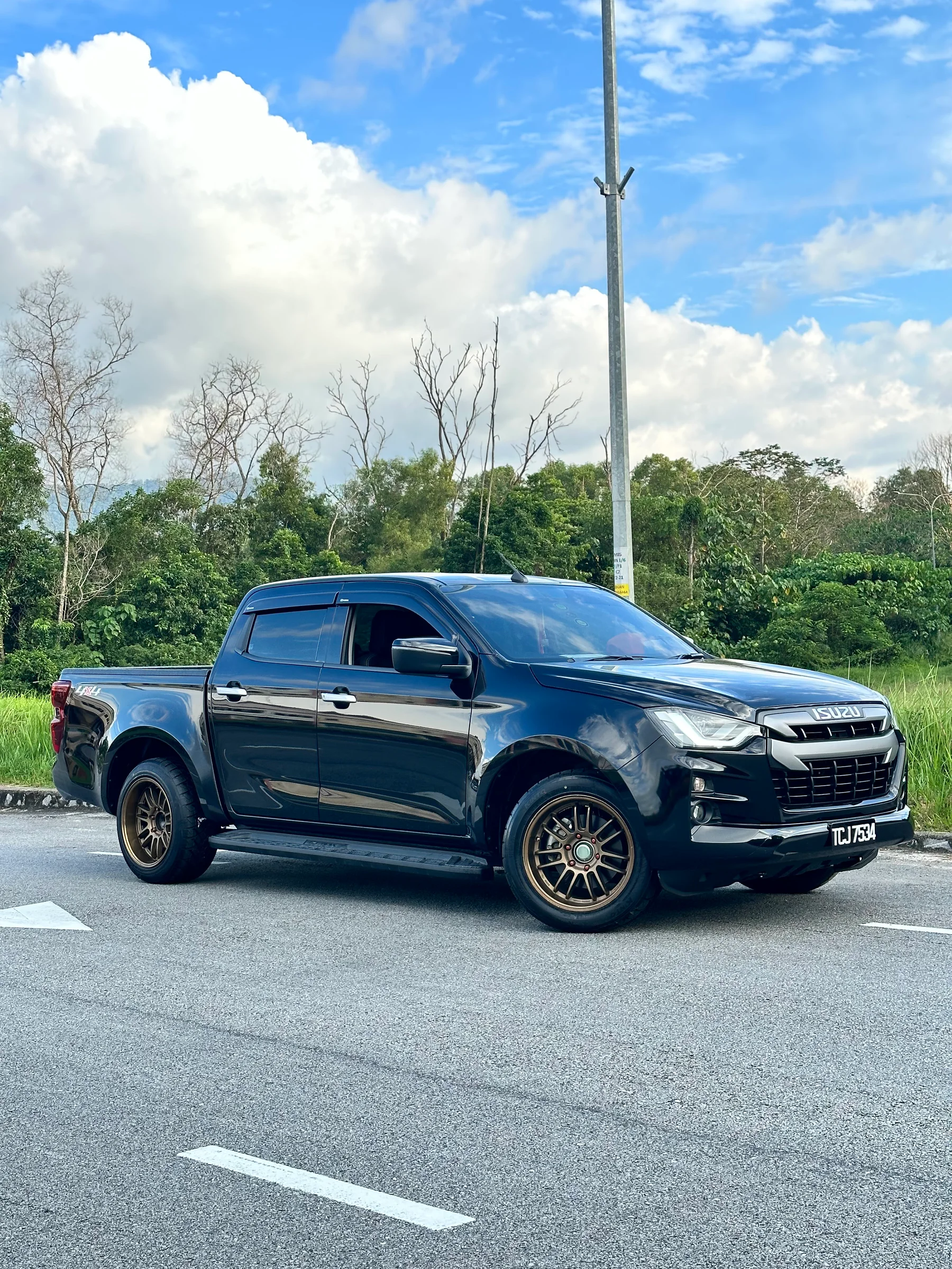 Black Isuzu D-Max pickup with bronze multi-spoke wheels