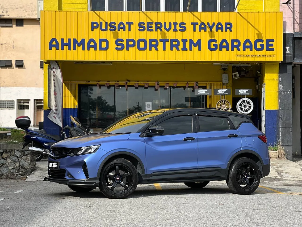 Blue Proton SUV with gloss black performance wheels outside ASG