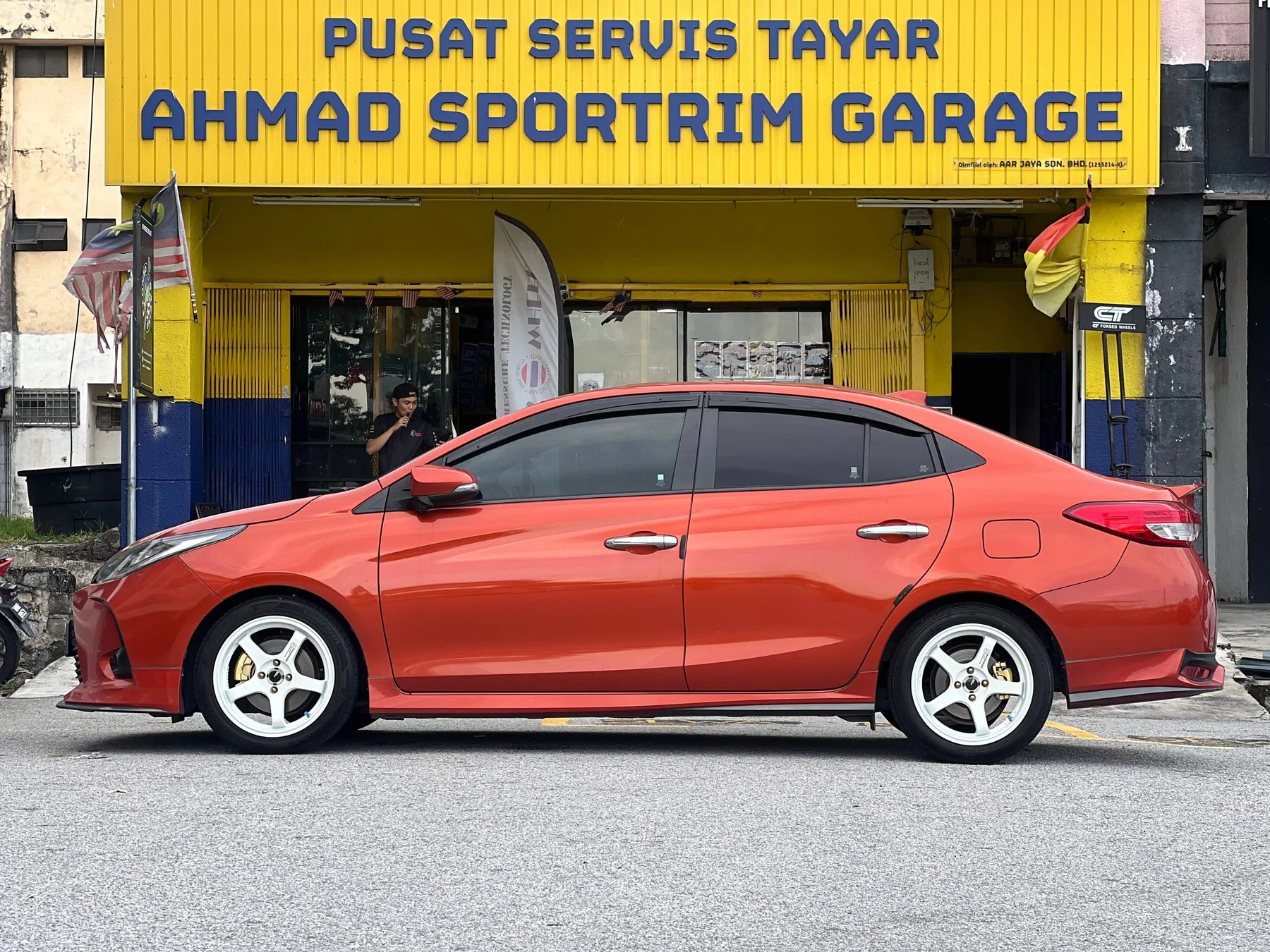 Red Toyota Vios side profile with white five-spoke wheels outside ASG
