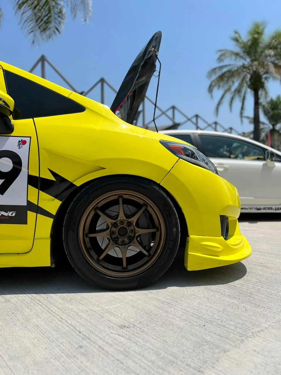 Neon yellow Honda with a bronze sport rim at an outdoor automotive event